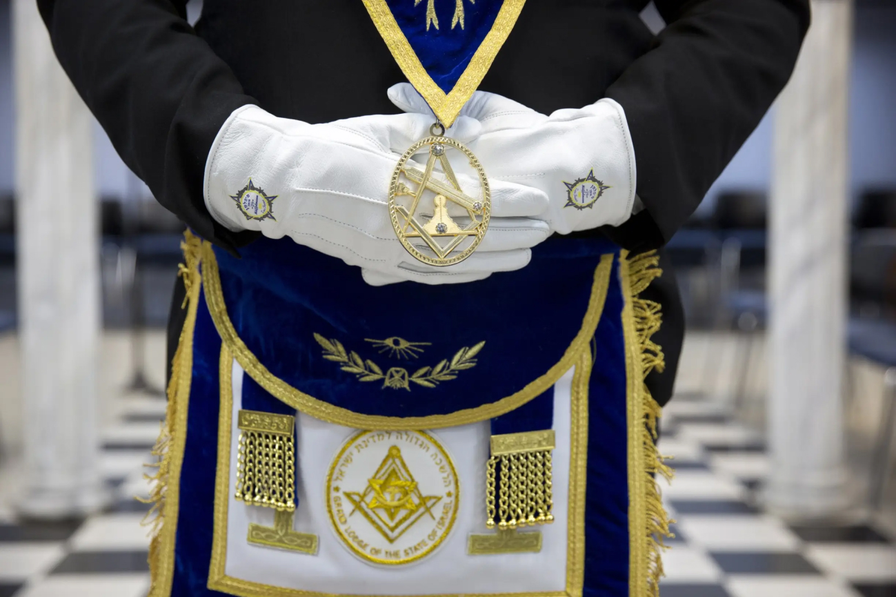 Man in suit wearing masonic apron and gloves