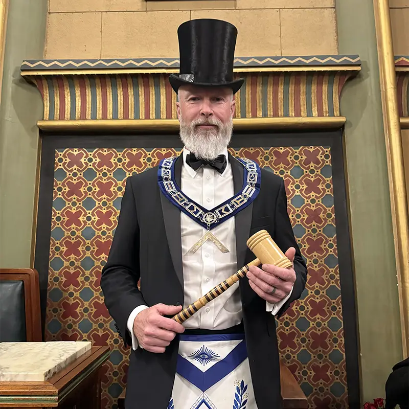 Frank Keller as Worshipful Master wearing a hat, square collar, and holding a gavel